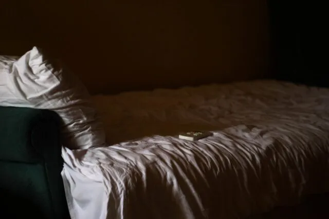 Dormitor cufundat în întuneric, cu o lumină slabă de la fereastră
